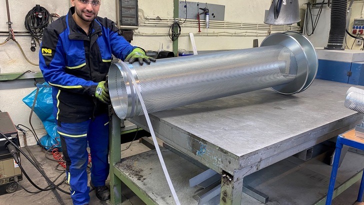 „Techniker in Arbeitskleidung inspiziert ein umfangreiches, isoliertes zylindrisches Bauteil aus Metall auf einer Werkbank, das für die Wärme- und Kältedämmung in industriellen Anwendungen optimiert ist.“. - © Redaktion TI „Techniker in Arbeitskleidung inspiziert ein umfangreiches, isoliertes zylindrisches Bauteil aus Metall auf einer Werkbank, das für die Wärme- und Kältedämmung in industriellen Anwendungen optimiert ist.“. - © Redaktion TI
