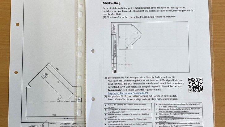 Die angehenden Industrie-Isolierer  sollen eine Dreitafelprojektion eines Zylinders mit Schrägstutzen zeichnen.