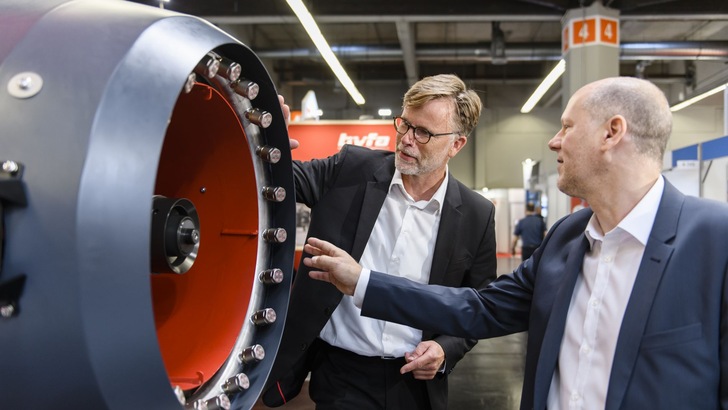 „Zwei Ingenieure in Anzügen begutachten moderne Dämmmaterialien und Isolierungstechnologien auf einer Fachmesse für Gebäudetechnik. - © NürnbergMesse/Uwe Niklas „Zwei Ingenieure in Anzügen begutachten moderne Dämmmaterialien und Isolierungstechnologien auf einer Fachmesse für Gebäudetechnik. - © NürnbergMesse/Uwe Niklas