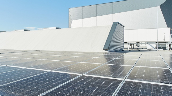 Ein möglich optimierter Alt-Text für das Bild könnte lauten: „Moderne Isoliermaterialien auf dem Dach eines Industriegebäudes mit integrierter Solartechnologie, zur Verbesserung der Energieeffizienz und Erfüllung aktueller Bauvorschriften.“. - © Rockwool
