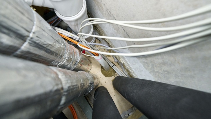 Gleich ein ganzes Bündel von Strom- und Datenkabeln wird mit einer „Conlit Bandage“ umwickelt und dann durch eine passende „Conlit 150 U Brandschutzschale“ geführt. Diese besteht aus Steinwolle, brennt nicht und verhindert zuverlässig, dass Feuer oder Rauch durch die Kernbohrung dringen.