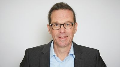 Mann mit Brille, Anzug und blauem Hemd vor schlichtem Hintergrund. - © Michael Kaffenberger-Küster