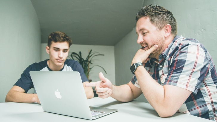 Vater und Sohn im Gespräch am Tisch vor Tablet