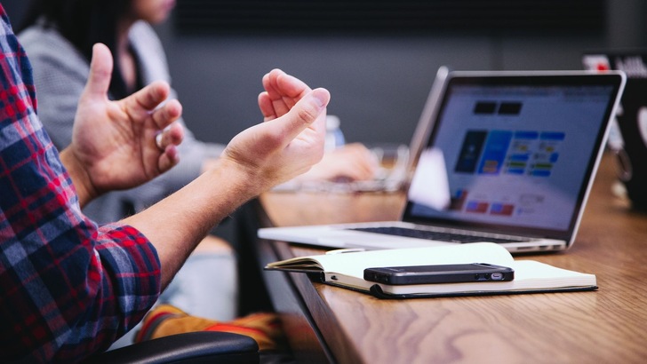 Bild zeigt gestikulierende Hände vor einem Bildschirm - Szene einer Online-Schulung - © Headway auf Unsplash