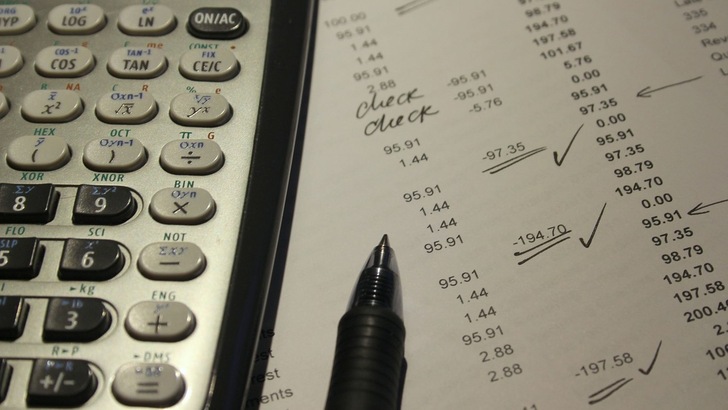 Taschenrechner und Stift liegen auf einem Blatt mit Zahlen