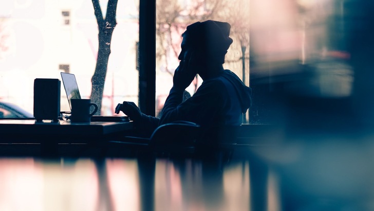 Mensch sitzt vor PC in Café und schaut auf den Bildschirm - © Hannah Wei Unsplash