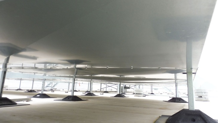 Das Bild zeigt eine eckige Luftleitung, welche mit Montageschienen auf ein Flachdach gestellt ist. Die Montageschienen für die Füße sind so gebaut, dass sie auf der unteren Seite die Blechummantelung durchdringen. Die etwas größeren Ausschnitte der Blechverkleidung dienen der Belüftung des Dämmsystems.