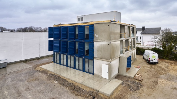 Ausrangierte Frachtcontainer als Module u. a. für den seriellen Bau von Hotels nutzt die Containerwerk eins GmbH. Bereits übernachten kann man in TIN INN Hotels, die aus solchen Containern bestehen, in Erkelenz und Montabaur. Quer auf dem Flachdach steht der Technikcontainer, aus dem in Schächten alle Leitungen zu und aus den Hotelzimmern geführt werden.