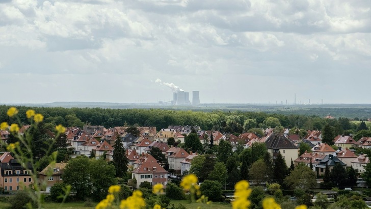 Ansicht auf einen Ortsteil, im Hintergrund ist ein Kraftwerk zu sehen