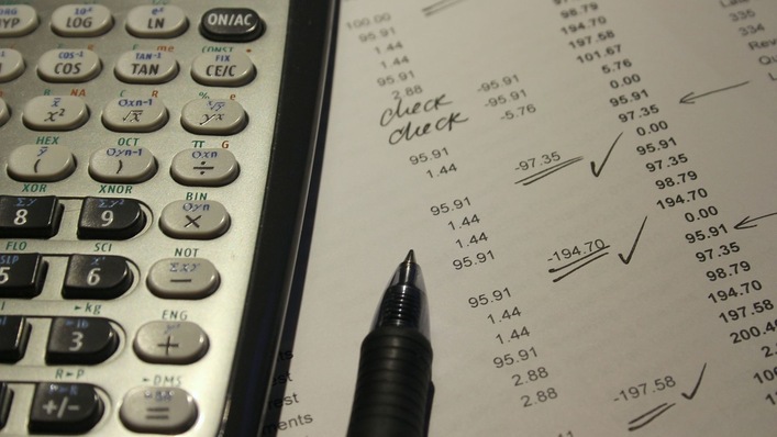 Taschenrechner und Stift liegen auf einem Blatt mit Zahlen