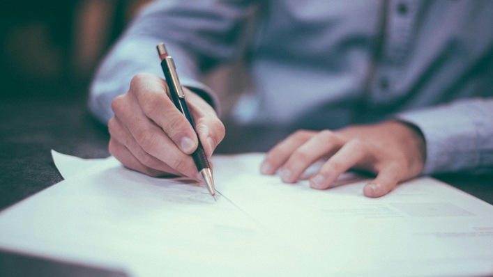 Mensch schreibt auf Ausdrucke