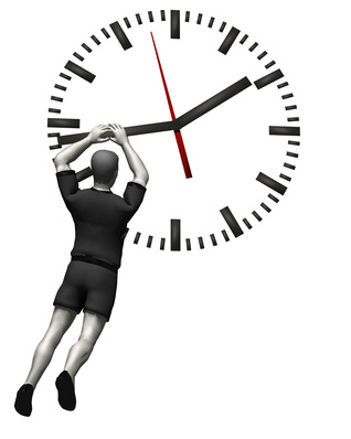 Eine Person in kurzen Hosen hängt an den Zeigern einer großen Uhr, als ob sie versuchen würde, die Zeit anzuhalten oder zu verschieben. - © Bild: i-picture - stock.adobe.com